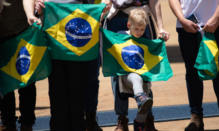 Repatriados da Ucrânia seguram a bandeira brasileira após chegarem no KC-390 Millennium da Força Aérea Brasileira em Brasília, em 10 de março de 2022 (Andressa Anholete/Getty Images)