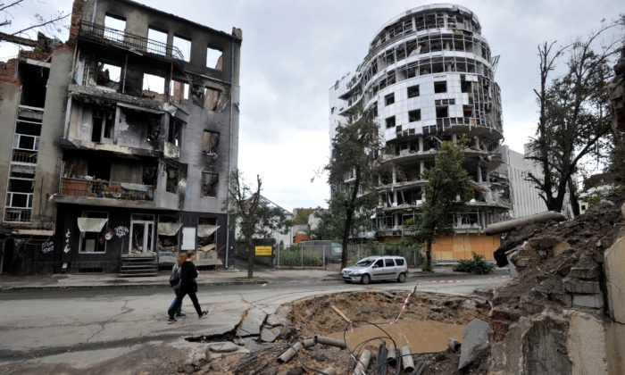 Pessoas passam por prédio destruído após bombardeio no centro de Kharkiv, na Ucrânia, em 18 de setembro de 2022 (Sergei Chuzavkov/AFP via Getty Images)