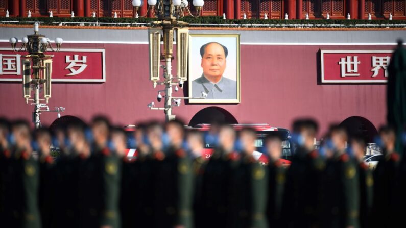 O retrato do falecido líder comunista, Mao Zedong, é visto atrás de policiais paramilitares enquanto eles se reúnem na Praça da Paz Celestial em Pequim antes de uma cerimônia que marca o 70º aniversário da entrada da China na Guerra da Coréia, em 23 de outubro de 2020 (Foto de NOEL CELIS/AFP via Getty Images)