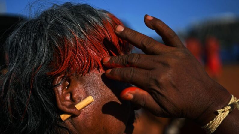 Um indígena da tribo Xavante aplica tinta vermelha no cabelo em um acampamento de protesto em Brasília, Brasil, em 25 de agosto de 2021 (Foto de CARL DE SOUZA/AFP via Getty Images)