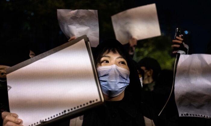 Manifestantes seguram um pedaço de papel branco contra a censura enquanto marcham durante um protesto contra as estritas medidas zero COVID da China, em Pequim, em 27 de novembro de 2022 (Kevin Frayer/Getty Images)