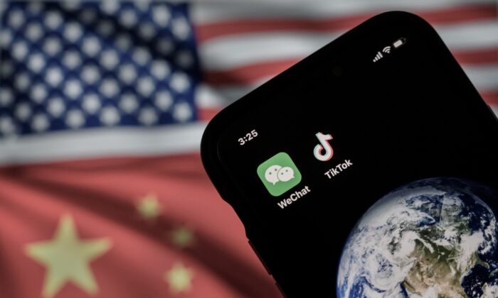 Um celular exibindo os logotipos dos aplicativos chineses WeChat e TikTok em frente a um monitor que mostra as bandeiras dos Estados Unidos e da China em uma página da internet, em Pequim, em 22 de setembro de 2020 (Kevin Frayer/Getty Images)