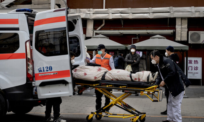 Motoristas de ambulância descarregam um paciente do lado de fora de uma clínica que trata pacientes com COVID-19 em Pequim em 21 de dezembro de 2022 (Kevin Frayer/Getty Images)
