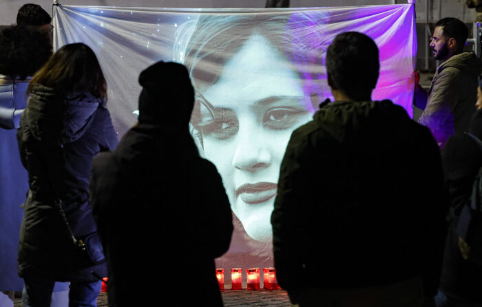 Manifestantes olham para uma imagem de Mahsa Amini durante uma vigília à luz de velas em frente à embaixada iraniana em memória das vítimas de tortura, violência sexual e enforcamentos, em Roma, Itália, 06 de janeiro de 2023 (EFE/EPA/FABIO FRUSTACI)