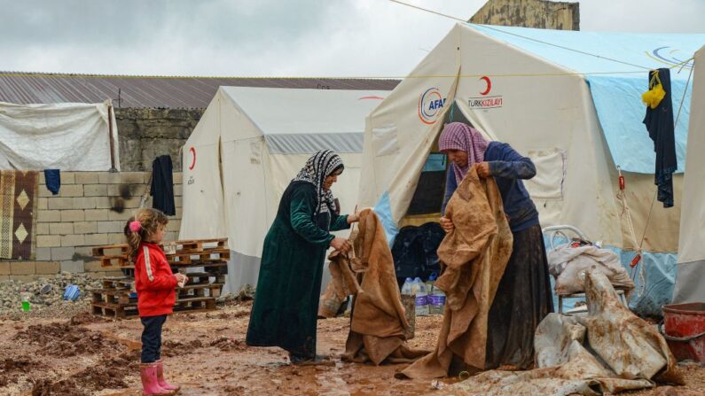 Mulheres limpam roupas cobertas de lama ao lado de tendas doadas pela organização humanitária turca Turk Kizilay, após inundações em Adiyaman, sudeste da Turquia, em 16 de março de 2023 (Foto de ILYAS AKENGIN / AFP via Getty Images)