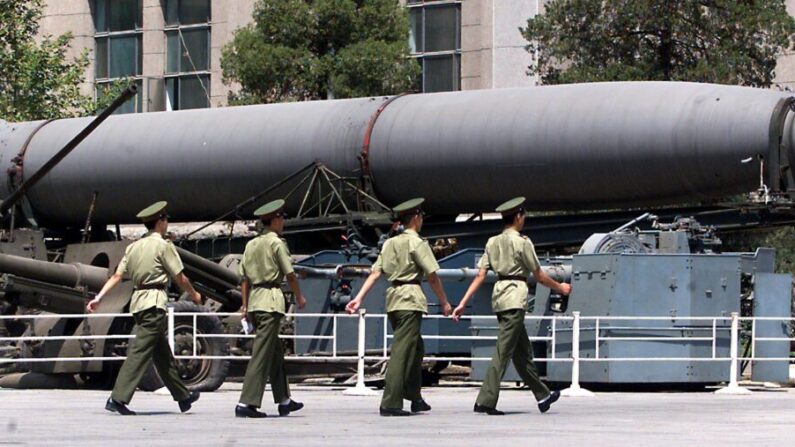 Quatro soldados do Exército de Libertação Popular (ELP) passam por um antigo míssil balístico chinês de médio alcance em exibição em frente ao museu militar de Pequim, em 26 de julho de 1999. (Stephen Shaver /AFP via Getty Images)