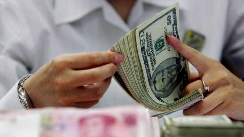 Um caixa de banco conta a pilha de yuans chineses e dólares americanos em um banco em Xangai, China, em 22 de julho de 2005. (STR/AFP/Getty Images)