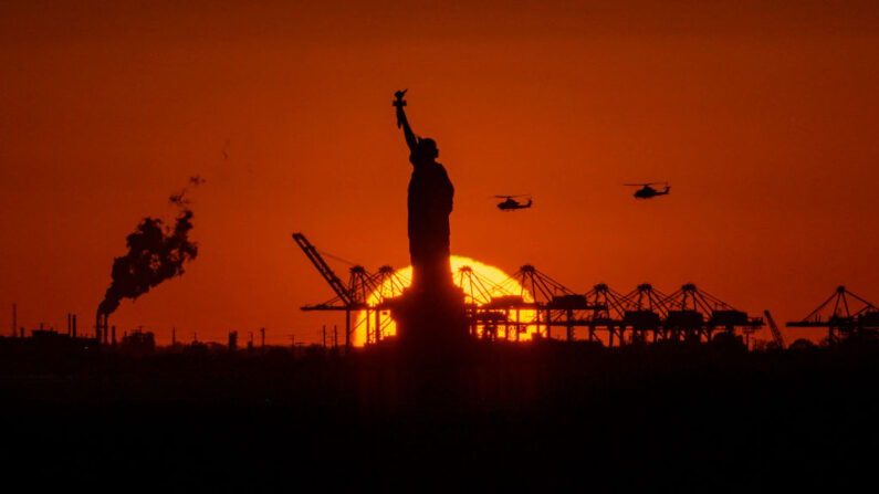 Helicópteros voam ao longe enquanto o sol se põe atrás da Estátua da Liberdade em Nova Iorque em 3 de novembro de 2022 (Foto de ANGELA WEISS/AFP via Getty Images)