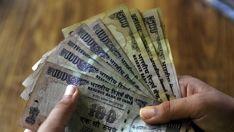 Um banqueiro indiano conta notas de 100 e 500 rupias indianas em um banco em Calcutá em 15 de julho de 2010. A Índia revelou quinta-feira um símbolo para a sua moeda rupia que espera que se torne tão globalmente reconhecido como sinais para o dólar, o iene, a libra e o euro (Crédito: DESHAKALYAN CHOWDHURY/AFP/GettyImages)
