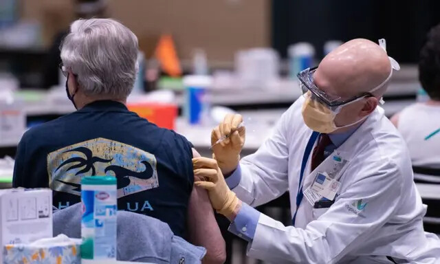 O diretor clínico John Corman, MD em Virginia Mason, administra uma dose da vacina Pfizer contra a COVID-19 no Amazon Meeting Center no centro de Seattle, Washington, em 24 de janeiro de 2021 (Grant Hindsley/AFP via Getty Images)