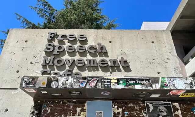 Um panfleto com uma imagem de Karl Marx pode ser visto na parede abaixo da placa do The Free Speech Movement Cafe em Berkeley, Califórnia, em 30 de julho de 2023. (Cortesia de Loretta Breuning)