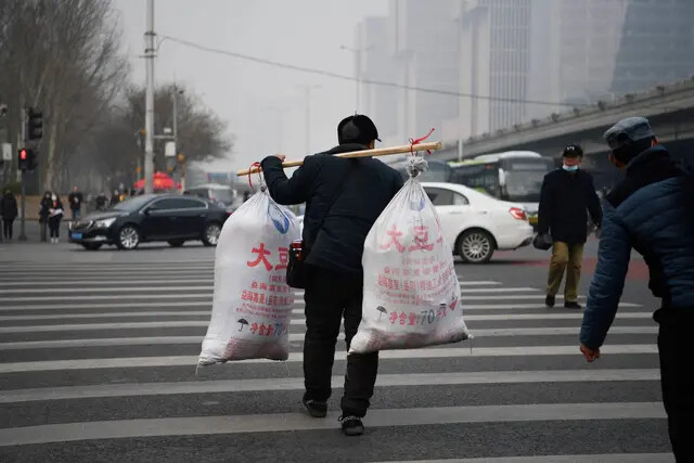 Um trabalhador atravessa uma estrada após chegar de ônibus de longa distância em Pequim, em 10 de março de 2021 (Greg Baker/AFP via Getty Images)
