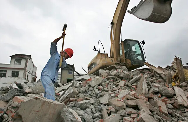 Um homem trabalha em um local de demolição na área de Bailianjing, no distrito de Pudong, onde casas residenciais estavam sendo demolidas em Xangai, China, em 28 de agosto de 2005. (China Photos/Getty Images)