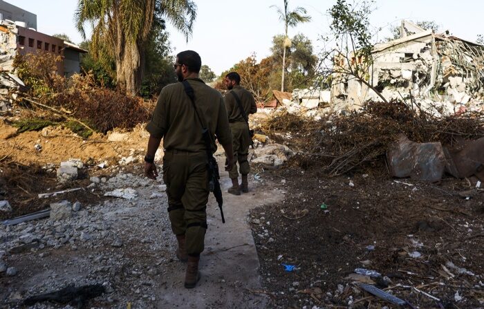 Soldados israelenses caminham perto de casas destruídas durante uma visita guiada da mídia ao destruído Kibutz Be'eri, Israel, 17 de outubro de 2023, que foi atacado pelo Hamas em 7 de outubro. Israel alertou todos os cidadãos da Faixa de Gaza para se deslocarem para o sul antes de uma esperada invasão (Kibutz) (EFE/EPA/MANUEL DE ALMEIDA)