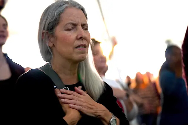 Uma mulher leva as mãos ao peito em oração durante um ministério em tenda em Bakersfield, Califórnia, em 12 de março de 2023 (Allan Stein/The Epoch Times)
