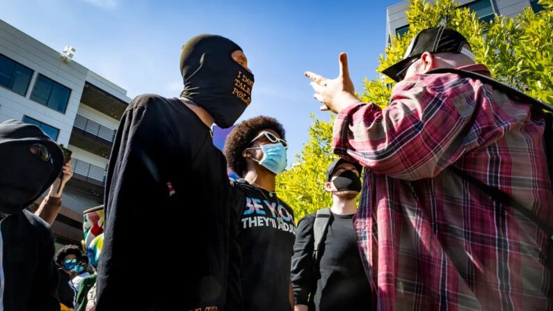 Manifestantes vestidos de preto confrontam um homem em Los Angeles, Califórnia, em 21 de outubro de 2021. (John Fredricks/The Epoch Times)