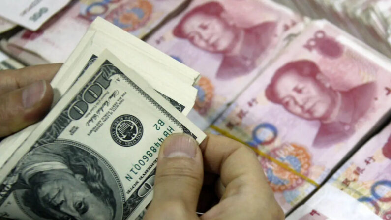 Notas de dólar americano eram contadas ao lado de pilhas de notas bancárias de 100 yuans (RMB) em um banco em Huaibei, na província de Anhui, leste da China, em 24 de setembro de 2013 (STR/AFP via Getty Images)