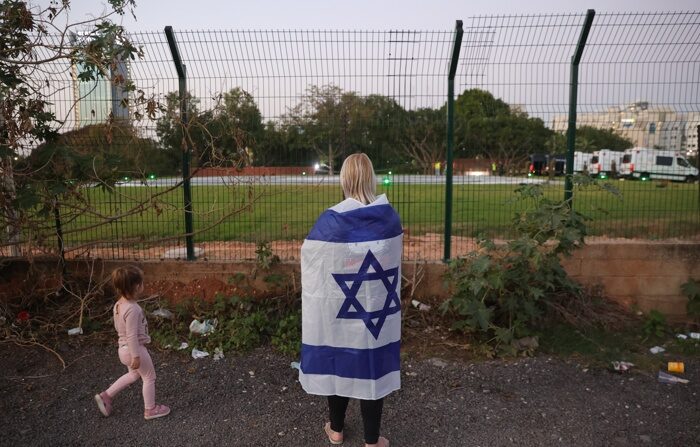 Uma mulher envolta em uma bandeira nacional esperando o retorno das crianças israelenses reféns mantidas pelo Hamas em Gaza, no Centro Médico Infantil Schneider em Petah Tikva, Israel, 24 de novembro de 2023   (Egito, Catar) (EFE/EPA/ABIR SULTAN)