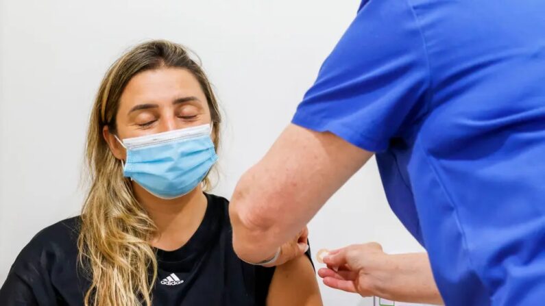 Uma mulher fecha os olhos após receber a vacina COVID-19 no Sydney Road Family Medical Practice em Balgowlah, em Sydney, Austrália, em 10 de janeiro de 2022. (Jenny Evans/Getty Images)