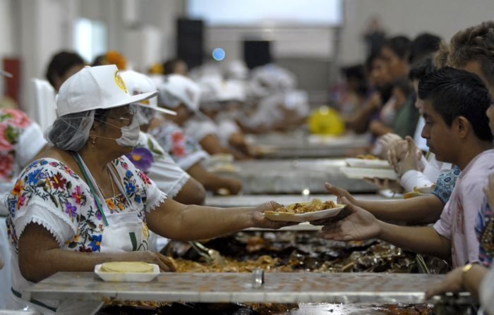 Mulheres distribuem porções de cochinita pibil. Imagem de arquivo. (EFE/Jacinto Kanek)