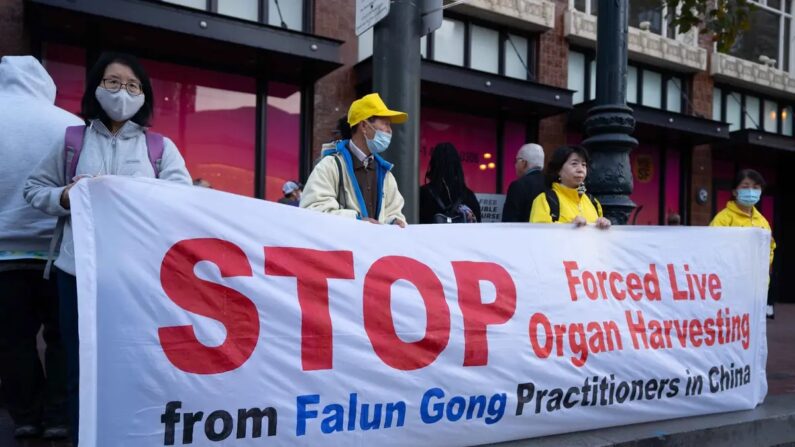 Praticantes do Falun Gong erguem uma faixa pedindo ao regime chinês que acabe com sua prática de extração forçada de órgãos, sancionada pelo Estado, em São Francisco, Califórnia, em 14 de novembro de 2023. (Zhou Rong/The Epoch Times)
