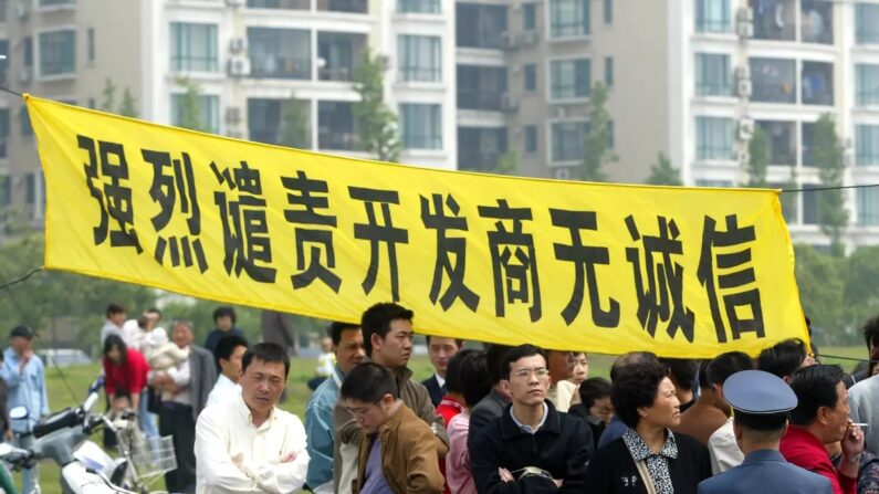 Proprietários penduram uma faixa que diz: “Condenamos veementemente o incorporador imobiliário desonesto”, para protestar na área residencial de Shanghai Cannes, em Xangai, China, em 14 de maio de 2006. (China Photos/Getty Images)
