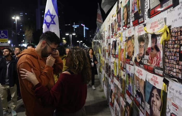 Pessoas choram ao lado de uma exposição de fotografias de reféns mantidos pelo Hamas em Gaza, durante uma manifestação pedindo sua libertação do lado de fora da base militar de Kirya, em Tel Aviv, Israel, em 6 de janeiro de 2024 (EFE/EPA/Abir Sultan)