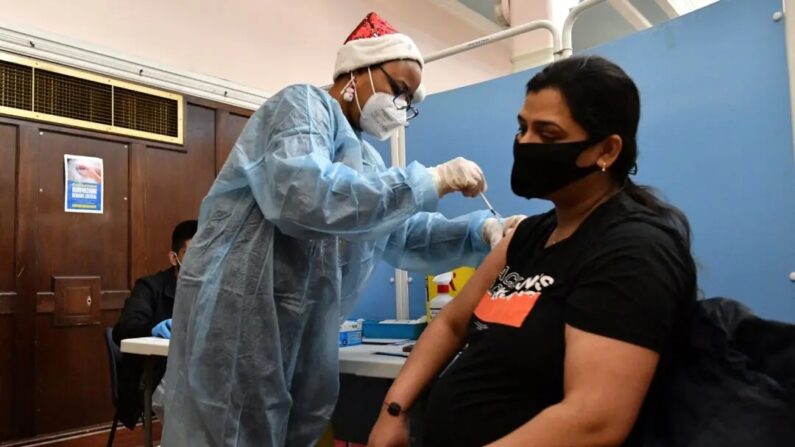 Um profissional de saúde administra uma dose da vacina contra a COVID-19 em uma mulher grávida em um centro de vacinação pop-up na prefeitura de Redbridge, no leste de Londres, em 25 de dezembro de 2021. (Justin Tallis/AFP via Getty Images)