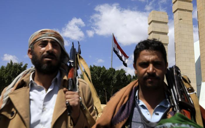 Houthis armados em frente a uma bandeira iemenita tremulando em Sana'a, Iêmen, em 15 de fevereiro de 2024 (EFE/EPA/YAHYA ARHAB)