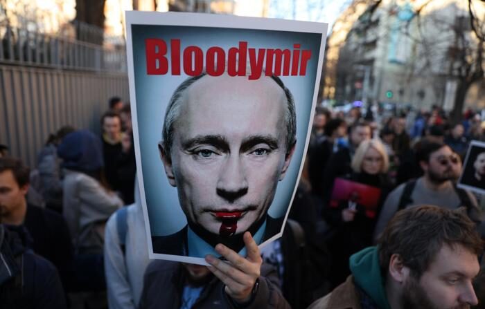 Um homem segura uma faixa com a imagem do líder russo Vladimir Putin, onde se lê "Bloodymir", durante uma vigília pelo falecido líder da oposição e ativista anticorrupção Alexei Navalny, após o anúncio de sua morte, em frente à Embaixada da Rússia em Belgrado, Sérvia, em 16 de fevereiro de 2024 (EFE/EPA/ANDREJ CUKIC)
