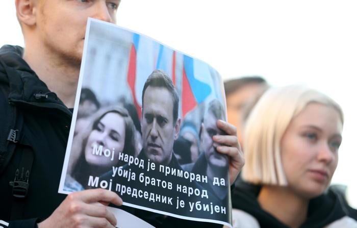 Um homem segura faixas com a imagem de Alexey Navalny e o texto "Meu povo é forçado a matar o povo de seu irmão, meu presidente foi assassinado" durante uma vigília pelo falecido líder da oposição e ativista anticorrupção Alexei Navalny após o anúncio de sua morte, em frente à Embaixada da Rússia em Belgrado, Sérvia, em 16 de fevereiro de 2024 (EFE/EPA/ANDREJ CUKIC)