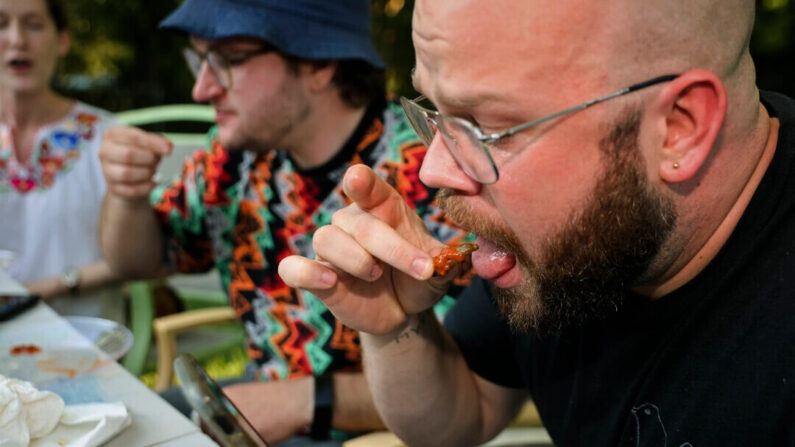Um grupo de amigos come insetos fritos como parte do desafio do Hot One, em Hyattsville, Maryland, em 4 de junho de 2021 (Chip Somodevilla/Getty Images)