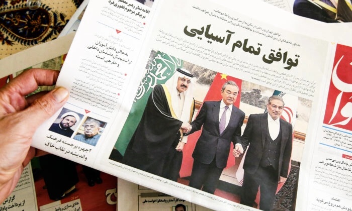 Um homem segura um jornal local reportando sobre o acordo intermediado pela China entre Irã e Arábia Saudita para restabelecer laços, na capital iraniana, Teerã, em 11 de março de 2023. (Atta Kenare/AFP via Getty Images)
