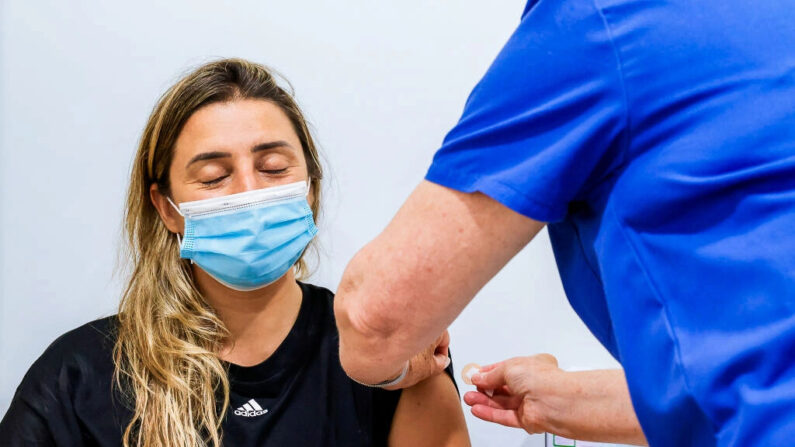 Uma mulher fecha os olhos após receber a vacina contra a COVID-19 no Sydney Road Family Medical Practice em Balgowlah, em Sydney, Austrália, em 10 de janeiro de 2022 (Jenny Evans/Getty Images)
