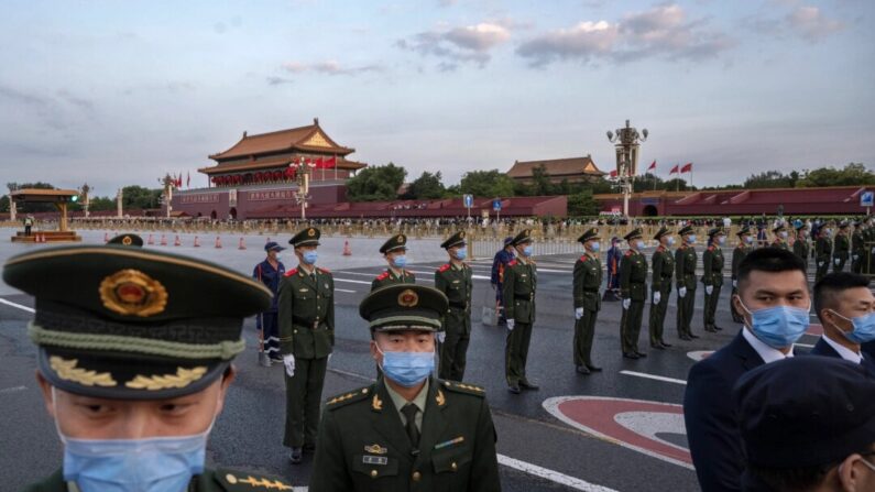 Policiais e seguranças bloqueiam o caminho enquanto realizam o controle de multidões após uma cerimônia oficial de hasteamento da bandeira para marcar o Dia Nacional próximo à Praça Tiananmen e à Cidade Proibida em 1º de outubro de 2021 em Pequim, China. (Kevin Frayer/Imagens Getty)