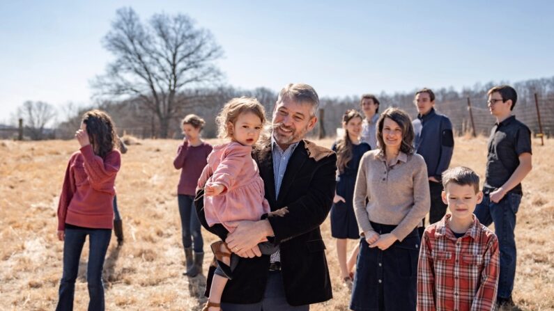 Paul Vaughn segura sua filha mais nova ao lado de sua esposa Bethany Vaughn e 8 de seus 11 filhos, no quintal de sua casa em Centerville, Tennessee, em 20 de fevereiro de 2024. (Samira Bouaou/The Epoch Times)
