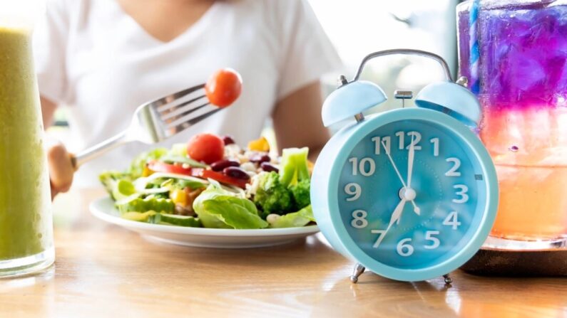 Um relógio azul costumava representar o jejum intermitente com uma salada saudável. (Nok Lek Travel Lifestyle/Shutterstock)
