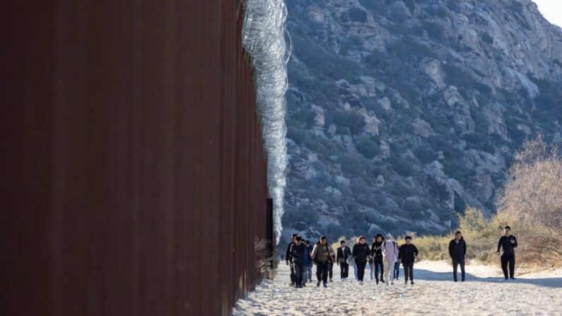 Migrantes que passaram por um vão no muro da fronteira dos Estados Unidos aguardam processamento por agentes da Patrulha de Fronteira em Jacumba, Califórnia, em 7 de dezembro de 2023. (John Fredricks/The Epoch Times)
