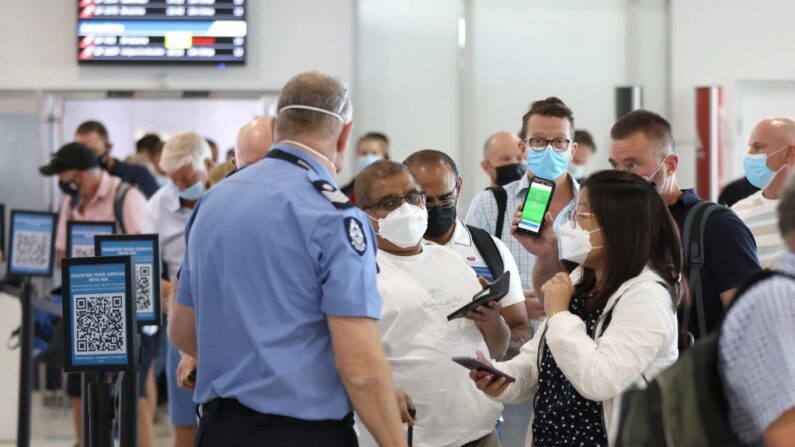 Passageiros chegando conversam com um policial da Polícia da Austrália Ocidental (WA) no Aeroporto Doméstico de Perth em 3 de março de 2022 em Perth, Austrália. (Paul Kane/Getty Images)