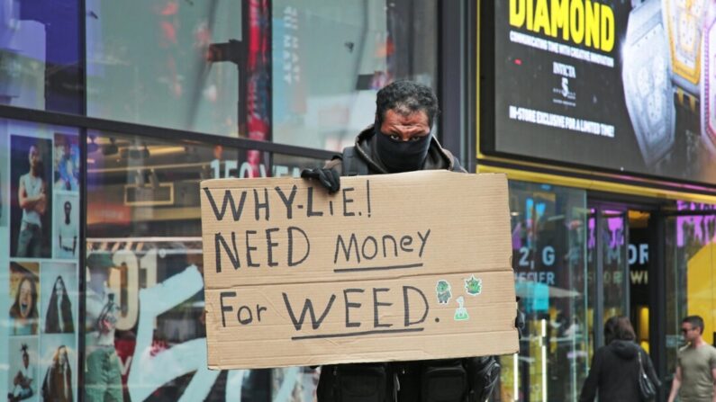 Um homem com uma placa na Times Square, em Nova Iorque, dizendo às pessoas que precisa de dinheiro para comprar maconha em 7 de junho de 2023. (Richard Moore/The Epoch Times)
