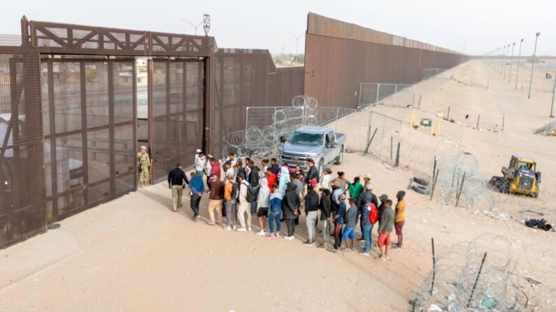Em uma vista aérea, imigrantes aguardam transporte e processamento após cruzarem a fronteira entre os EUA e o México em El Paso, Texas, em 13 de março de 2024. (John Moore/Getty Images)
