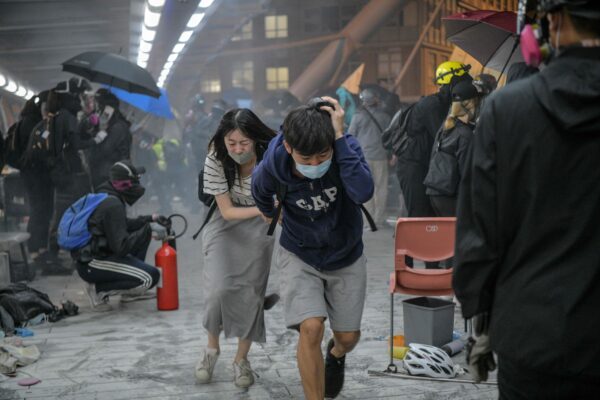 Manifestantes correm para se esconder depois que a polícia de choque disparou gás lacrimogêneo em direção à ponte que eles tentavam subir para escapar do campus da Universidade Politécnica de Hong Kong e da polícia, no distrito de Hung Hom, em Hong Kong, em 18 de novembro de 2019 ( Anthony Wallace / AFP via Getty Images)