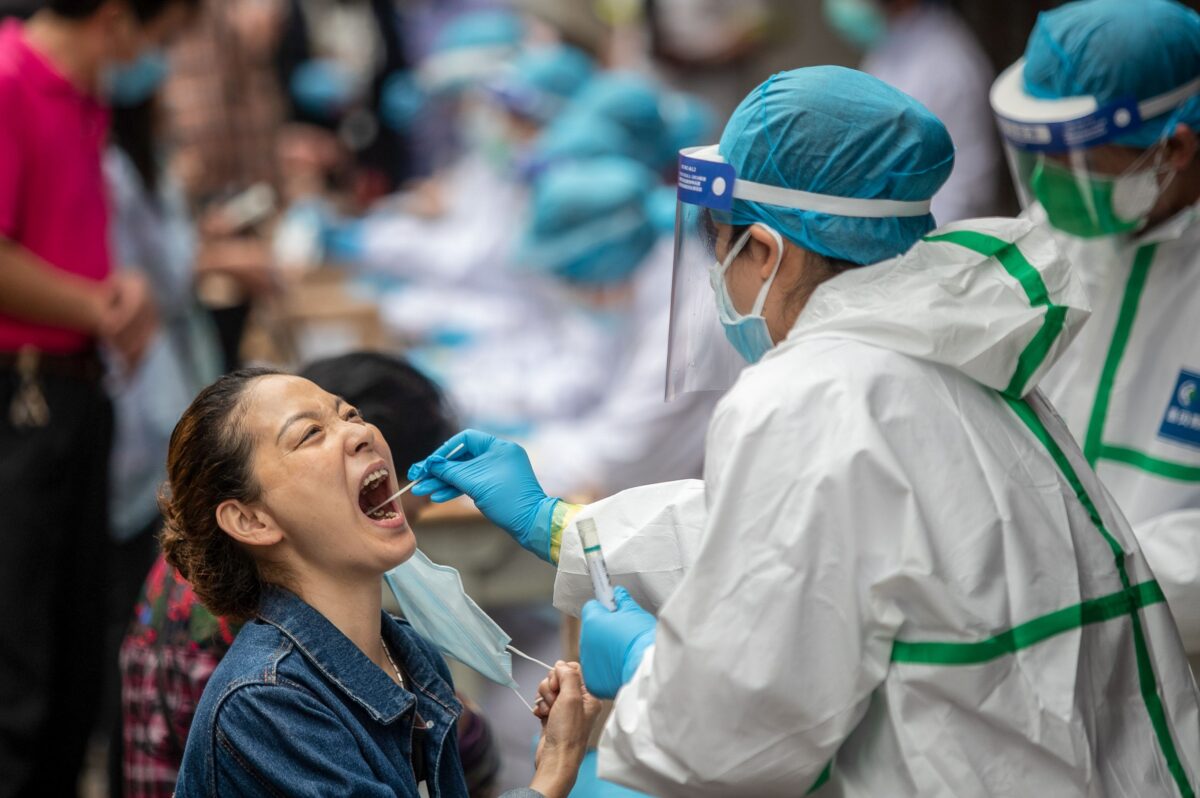 Um trabalhador de saúde coleta uma amostra de zaragatoa de uma residente para testar o vírus do PCC em Wuhan, China, em 15 de maio de 2020 (STR / AFP via Getty Images)