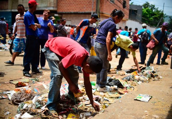 Pessoas procuram comida fora de um supermercado saqueado no bairro de El Valle, em Caracas, em 21 de abril de 2017 (RONALDO SCHEMIDT / AFP via Getty Images)