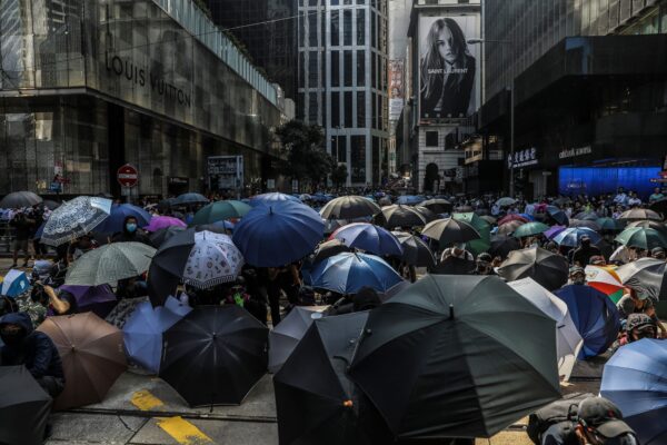 Manifestantes se protegem sob um guarda-chuva enquanto a polícia chega durante um protesto flash mob no distrito central de Hong Kong em 13 de novembro de 2019. (Dale De La Rey / AFP via Getty Images)