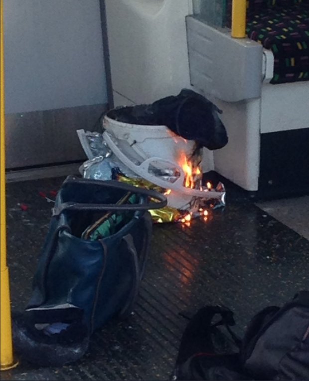 Pertences pessoais e um balde com um item em chamas são vistos no chão de um vagão do metrô na estação Parsons Green, a oeste de Londres (Rigs via Storyful/Twitter)