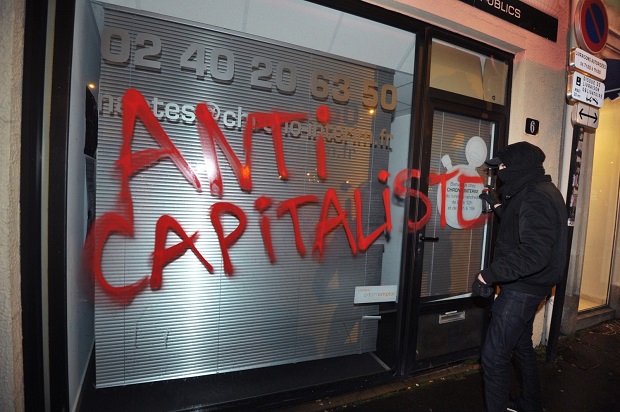 Membro do grupo radical Antifa vandaliza fachada de uma loja em Nantes, na França, em 14 de fevereiro de 2014 (Frank Perry/AFP/Getty Images)