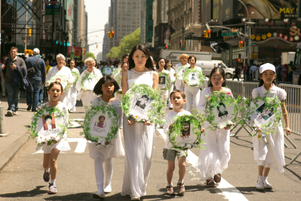 Jovens praticantes do Falun Dafa carregam retratos de outros praticantes que foram mortos na perseguição ocorrida na China, durante um desfile em Nova York em 15 de maio de 2015 (Benjamin Chasteen/Epoch Times)