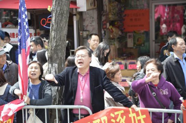 Michael Chu (centro), líder da comunidade chinesa na cidade de Nova York, amaldiçoa e ameaça os praticantes do Falun Gong durante um desfile em Flushing, no bairro de Queens, em Nova York, em 26 de abril de 2014. Chu dirige uma organização dedicada a assediar os praticantes do Falun Gong. (Gary Du/The Epoch Times)