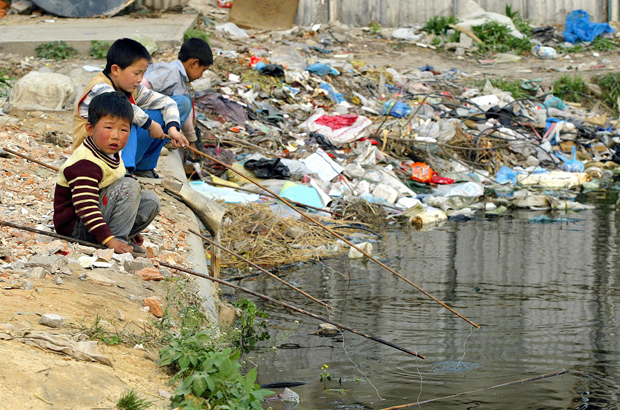 China, lixo, reciclagem, poluição - Crianças pescam em águas cheias de lixo descartado e não tratado em Xangai em 14 de junho de 2004 (Liu Jin/AFP/Getty Images)